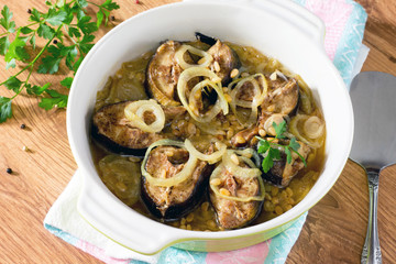 Baked fish (mackerel) on a bed of onion with pine nuts