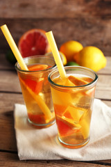 Iced tea with lemon and grapefruit on wooden background