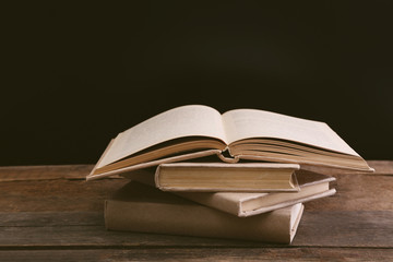 Old books on wooden table against black background