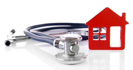 Concept of family medicine - red plastic house and stethoscope isolated on white background