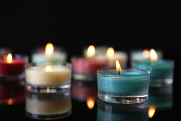 Colourful alight candles in a row on black background, blurred