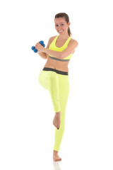 Pretty woman doing wearing sports neon yellow bra and leggings doing exercises for press muscles in a standing position using two blue dumbbells on white isolated background.