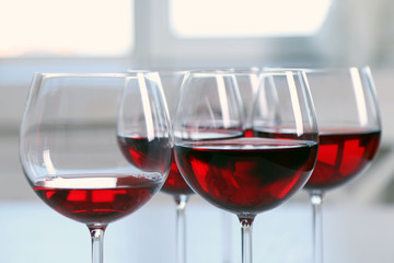 Glasses of red wine on table on bright background