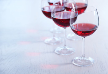 Glasses of red wine on table on bright background