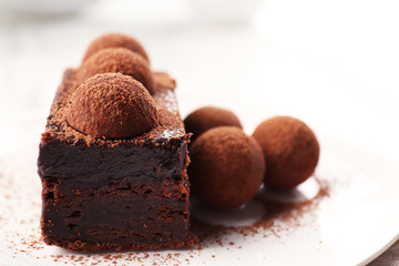 Slice of chocolate cake with a truffle on plate closeup