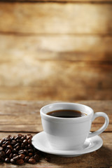 Cup of coffee and coffee grains on wooden background