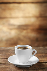 Cup of coffee and coffee grains on wooden background