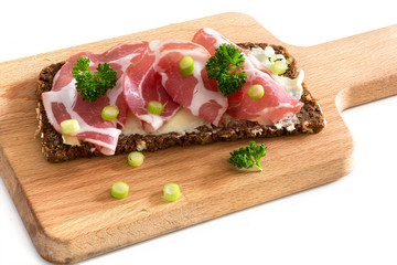 Italian coppa or capicola ham on dark bread on a wooden cutting