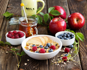 Healthy breakfast with granola, apples, blueberries and raspberries.