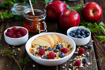 Healthy breakfast with granola, apples, blueberries and raspberries.