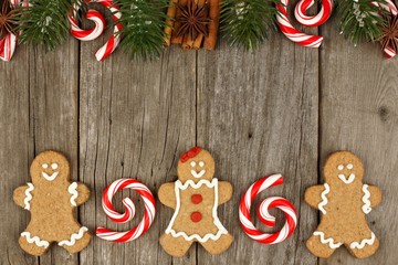 Christmas gingerbread cookies and peppermints on rustic wooden background with holiday top border