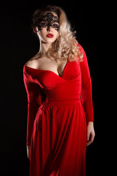 Young lady in a red evening dress and a black mask