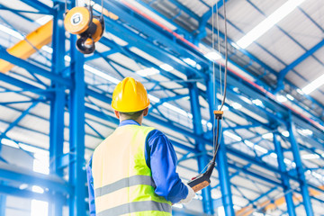 Fototapeta premium Worker in factory controlling crane with remote