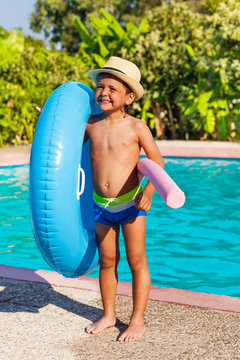 Boy In Hat Holding Inflatable Ring And Pool Noodle