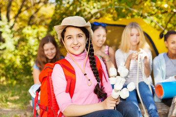 Girl wearing hat holds marshmallow sitting