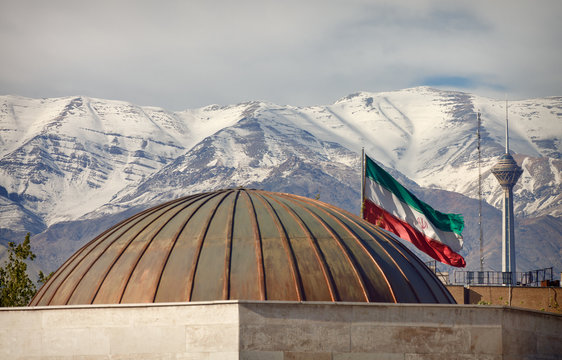 Iran Flag and Milad Tower in Front of Snow Covered Alborz Mountains