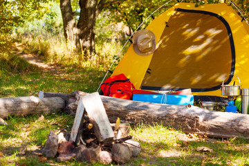Campsite with tent, rucksack, bonfire at daytime