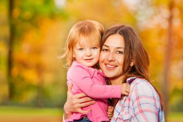 Fototapeta na wymiar Happy mom and little blond portrait in autumn park