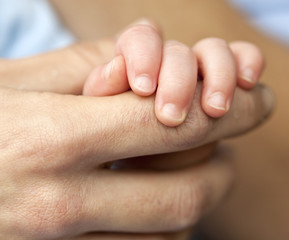Holding my Father's Finger. A young baby boy holds onto his father's finger.  A contrast between the young baby hand and skin and the hard worked skin of his father.