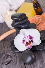 Spa treatment with black stones, bath salt, essential oil, soap, and towel close up 