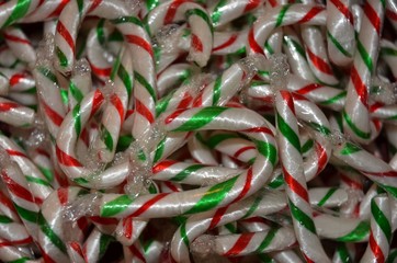 White, red and green small candy canes piled haphazardly on a table