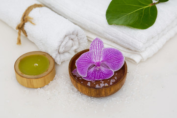 Fototapeta na wymiar Pink orchid with salt in bowl and green leaf ,towel, candle with pile of salt 
