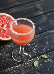 Fresh grapefruit juice in glass on dark wooden surface