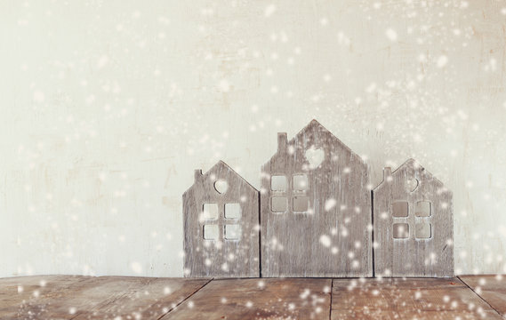 high key image of vintage wooden house decor on wooden table. retro filtered. selective focus. snow overlay
