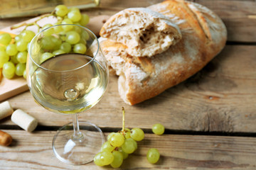 Still life of wine, grape, cheese and bread on rustic wooden background