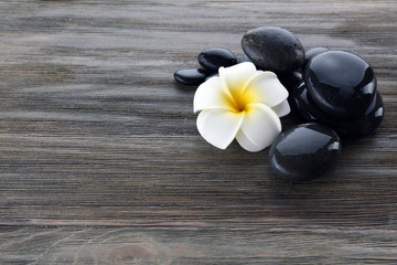 Wet spa stones with flower on wooden background
