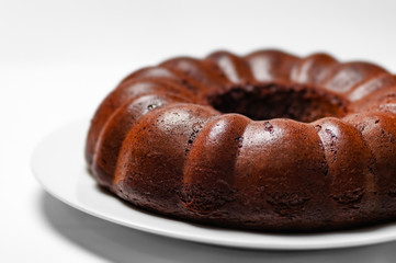 Chocolate bunt cake whole sponge on a plate white background closeup 