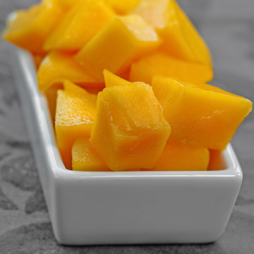 Diced mango cubes placed and served on a white dish square composition