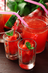 Cold watermelon desserts and drinks in glasses, on wooden table background