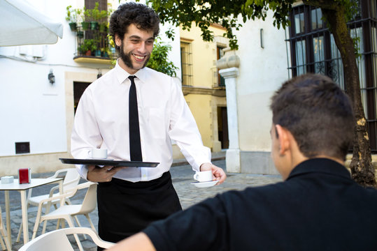 Waiter serving coffee on a terrace