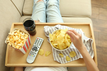 A girl with a tray having lunch on a sofa, close-up
