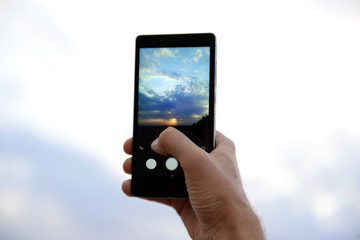 Man using smart phone for taking photo of beautiful sky