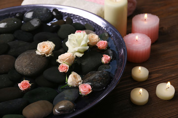 Spa composition of flowers and stones in water on wooden background