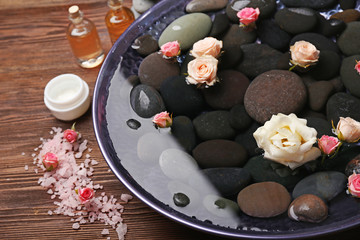 Spa composition of flowers and stones in water on wooden background