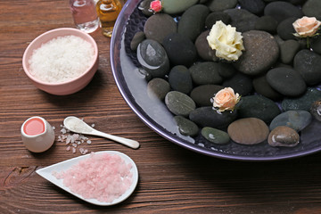 Spa composition of flowers and stones in water on wooden background