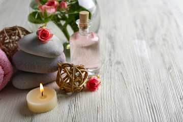 Fototapeta na wymiar Composition of flowers, candles and stones on white wooden background, in spa salon