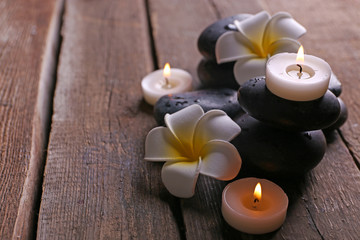 Fototapeta na wymiar Relaxing composition with exotic fragipani flower, pebbles and candles on wooden background