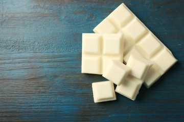 White chocolate pieces on color wooden background