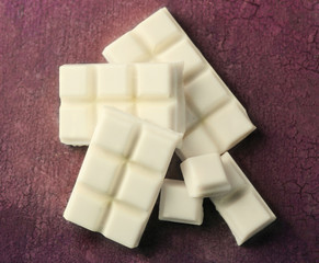 White chocolate pieces on color wooden background