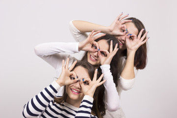 Three girls, looking trought theirs hands circle, as eyewear.