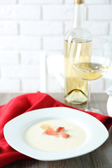 Tasty salmon cream soup with wine and red cotton serviette on wooden table, close up