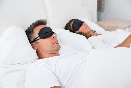 Couple Sleeping On Bed Using Eye Mask