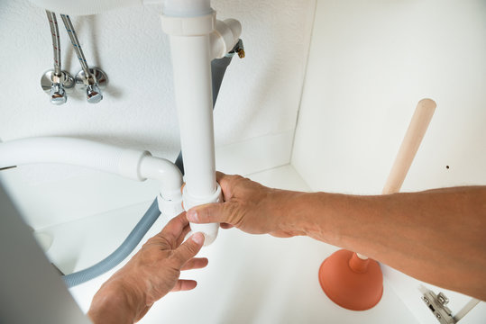 Plumber Working On Pipes Under Kitchen Sink