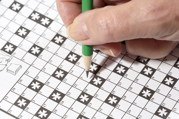 An elderly woman is doing crossword puzzle. It is a good exercise for brains especially for older people. It is a relaxing habit to spend some time alone.