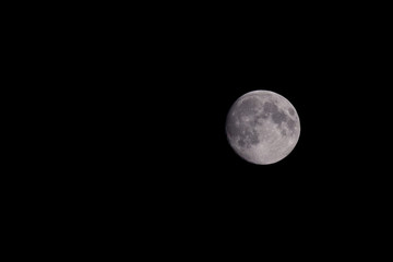 Closeup of beautiful silver full moon over dark black sky 
