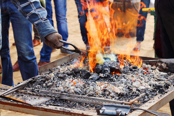Burning coals with bright orange flame and hand of blacksmith wi